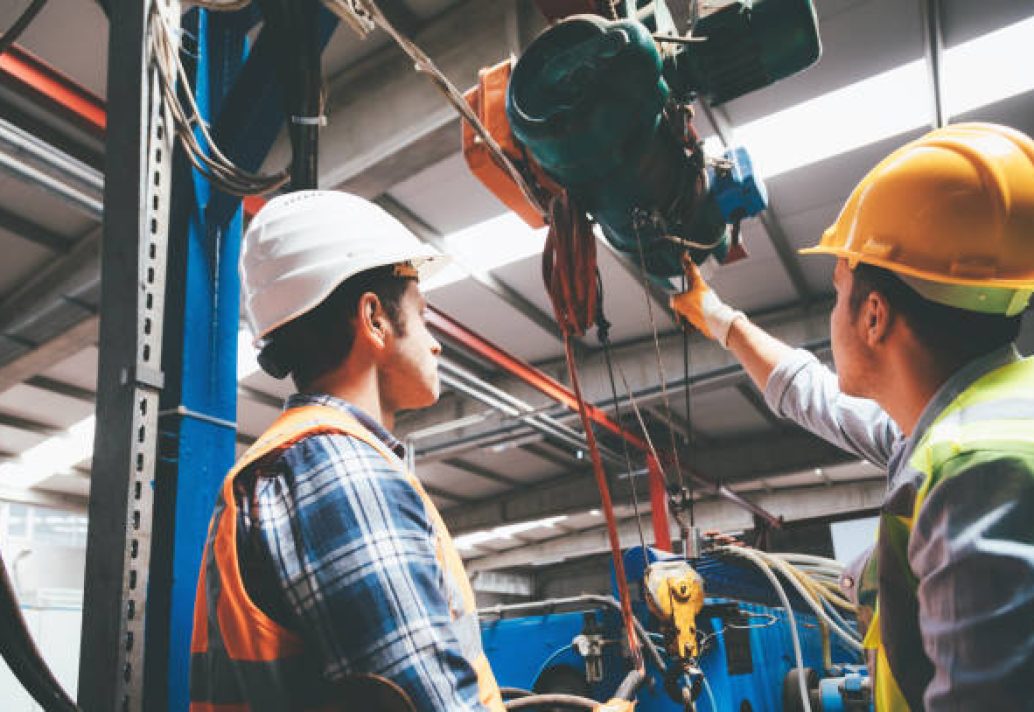 Skilled Industry worker and manager man using overhead crane controller and pushing button while managing crane at industrial tractor plant shop
